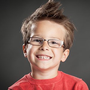 Young boy in red wearing glasses smiling