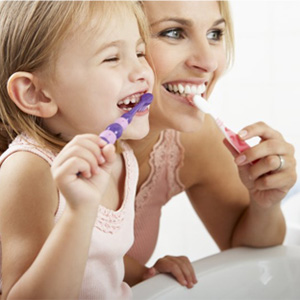 A mother and daughter brushing their teeth.