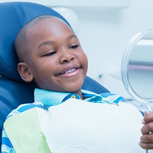 Young boy in dental chair, smiling at himself in mirror