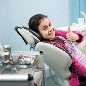child at the dentist’s office giving a thumbs-up