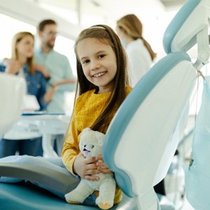 Child smiling while dentist and parents talk in treatment room