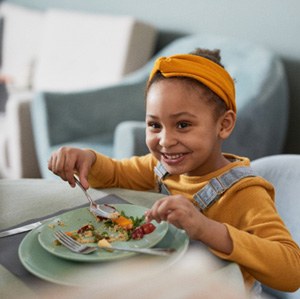Child smiling at parent while eating meal