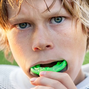 Child putting on green mouthguard