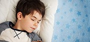 young boy sleeping on bed