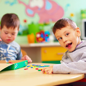 Two kids with special needs playing with toys at a table