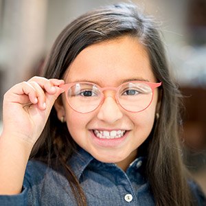 Young girl holding glasses grinning