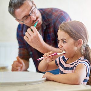 Father and daughter brushing teeth