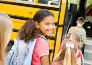 child smiling and getting into a school bus