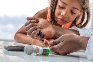 child learning how to check their blood sugar