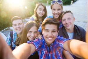 A group of smiling teenagers after seeing a pediatric dentist