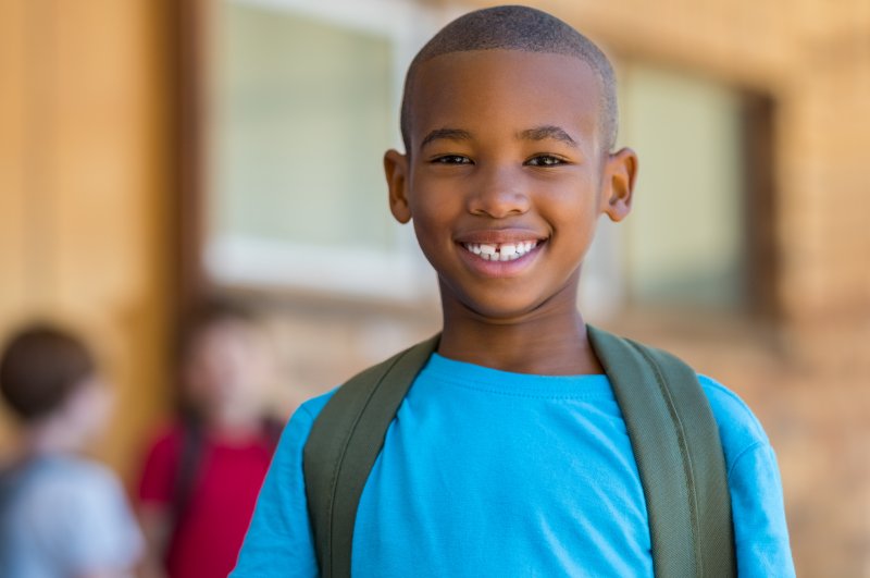 Child in blue shirt smiling at school