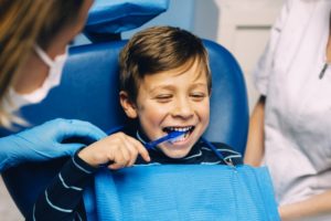 boy brushing his teeth in dental chair to preserve his tooth enamel 