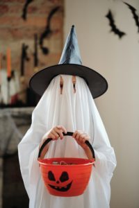 Child in Halloween costume holding candy bucket