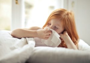 Young girl blowing her nose in tissue