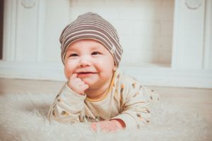 Smiling baby chewing on finger
