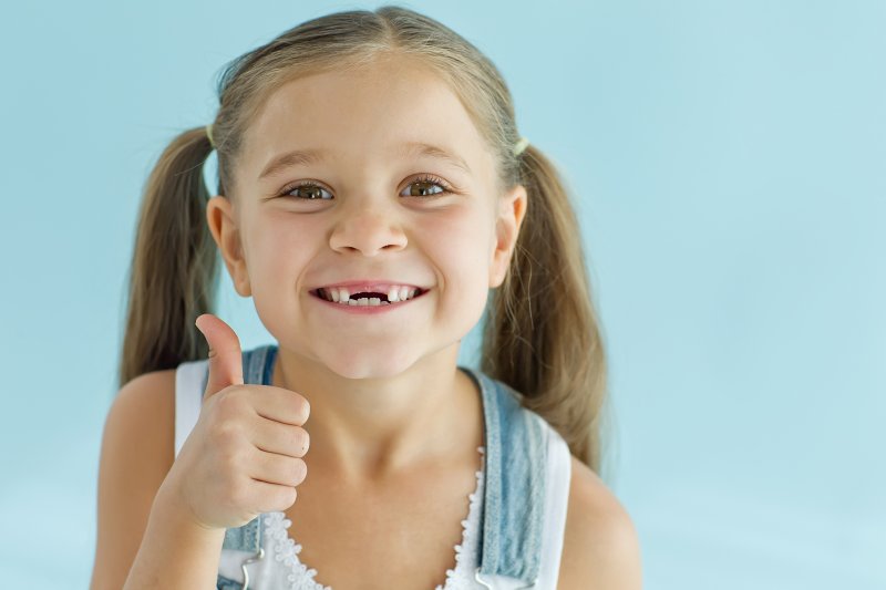 A girl with missing teeth giving a thumbs-up