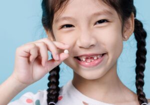 Happy young girl holding her extracted tooth