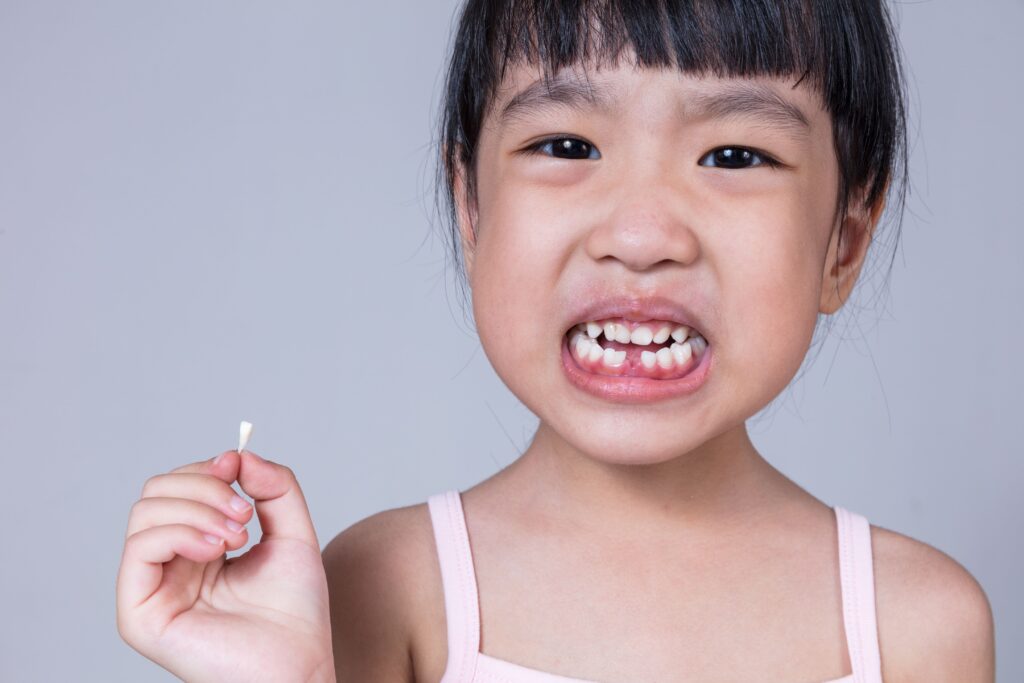 Little girl holding knocked-out tooth