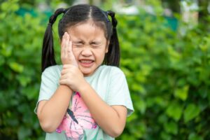 Child wincing and holding mouth in pain.